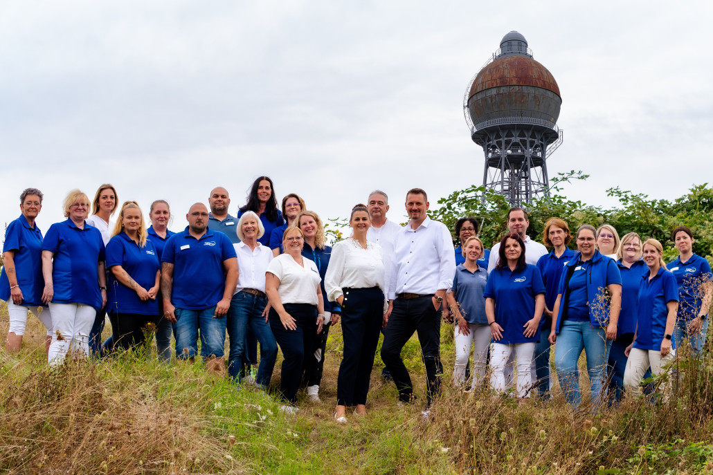 Mitarbeiter der Firma Gloger Pflegedienste auf einer Wiese vor dem Ilseder Wasserturm